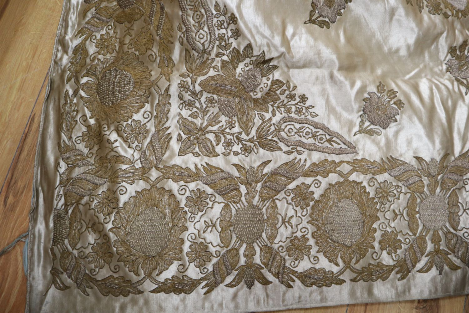 A silk bed cover, heavily embroidered in gold and silver coloured threads, silk lined in pale blue silk, 126 x 120cm